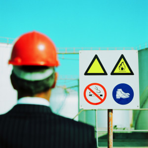 Businessman Wearing a Hard-Hat Looking at a Hazard Sign