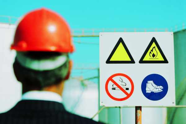 Businessman Wearing a Hard-Hat Looking at a Hazard Sign
